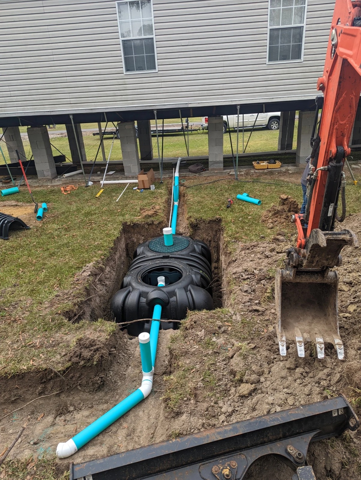 A MO-DAD treatment tank set in its excavation beside a raised mobile home.